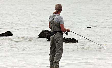 A fisherman in deck boots is fishing